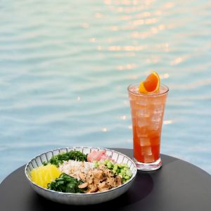 Poke bowl and iced orange drink beside water