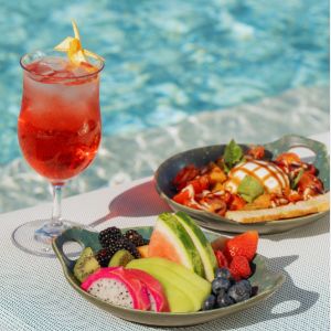 Fresh fruit platter, dessert, and red drink by poolside