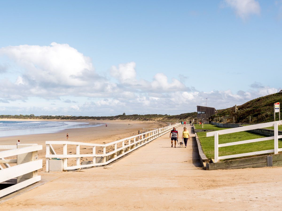 Beach walkway leading along a sandy coastline.