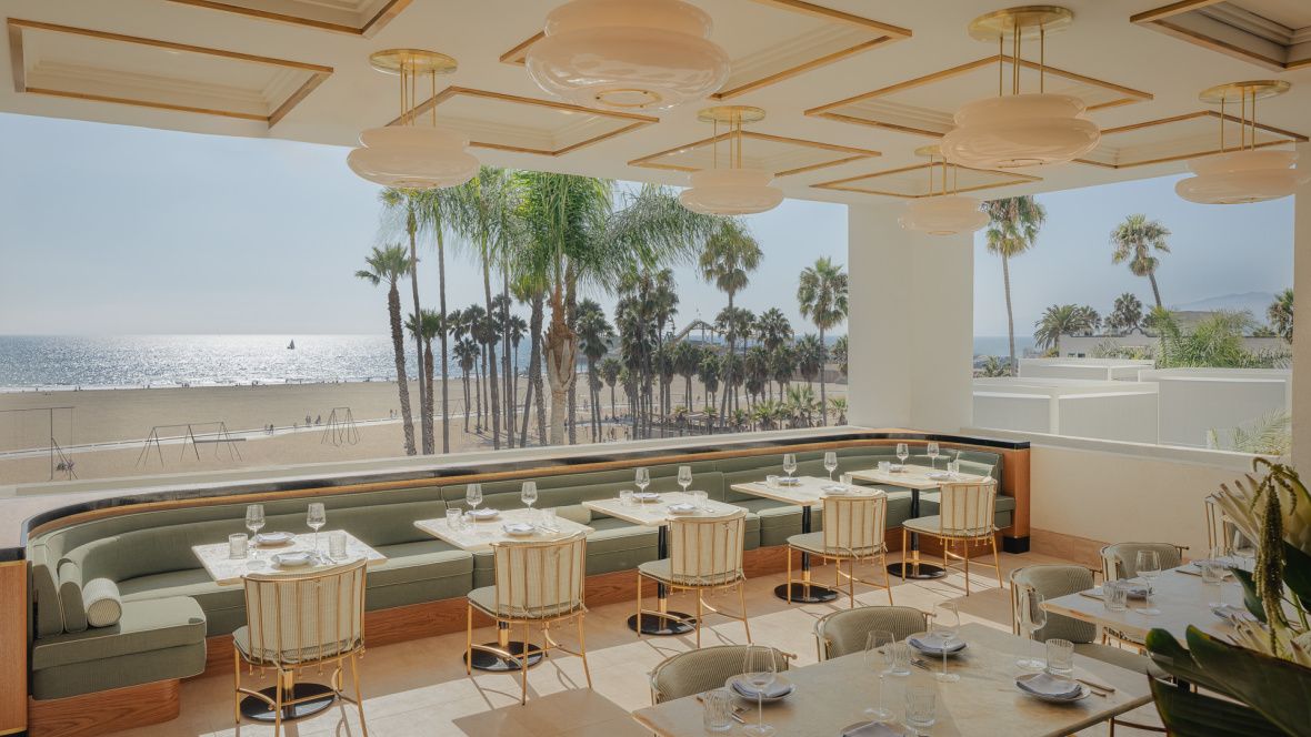 outdoor seating overlooking palm trees, sandy beach and pacific ocean