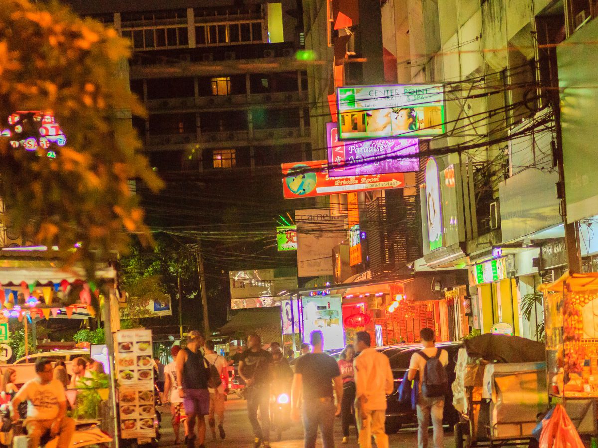 Bustling night market street with vibrant neon lights.