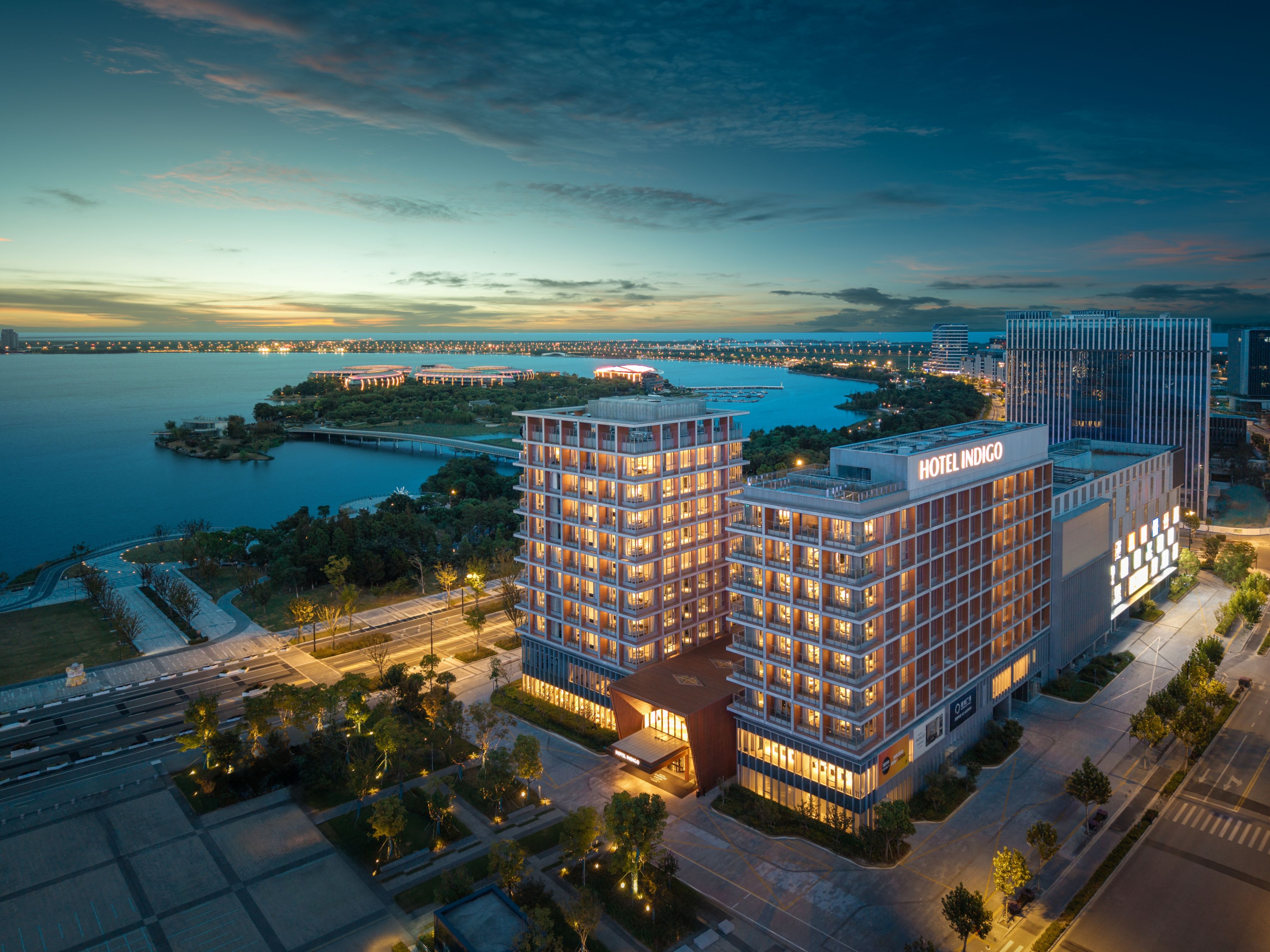 Exterior of building at dusk, by the water, with city skyline views