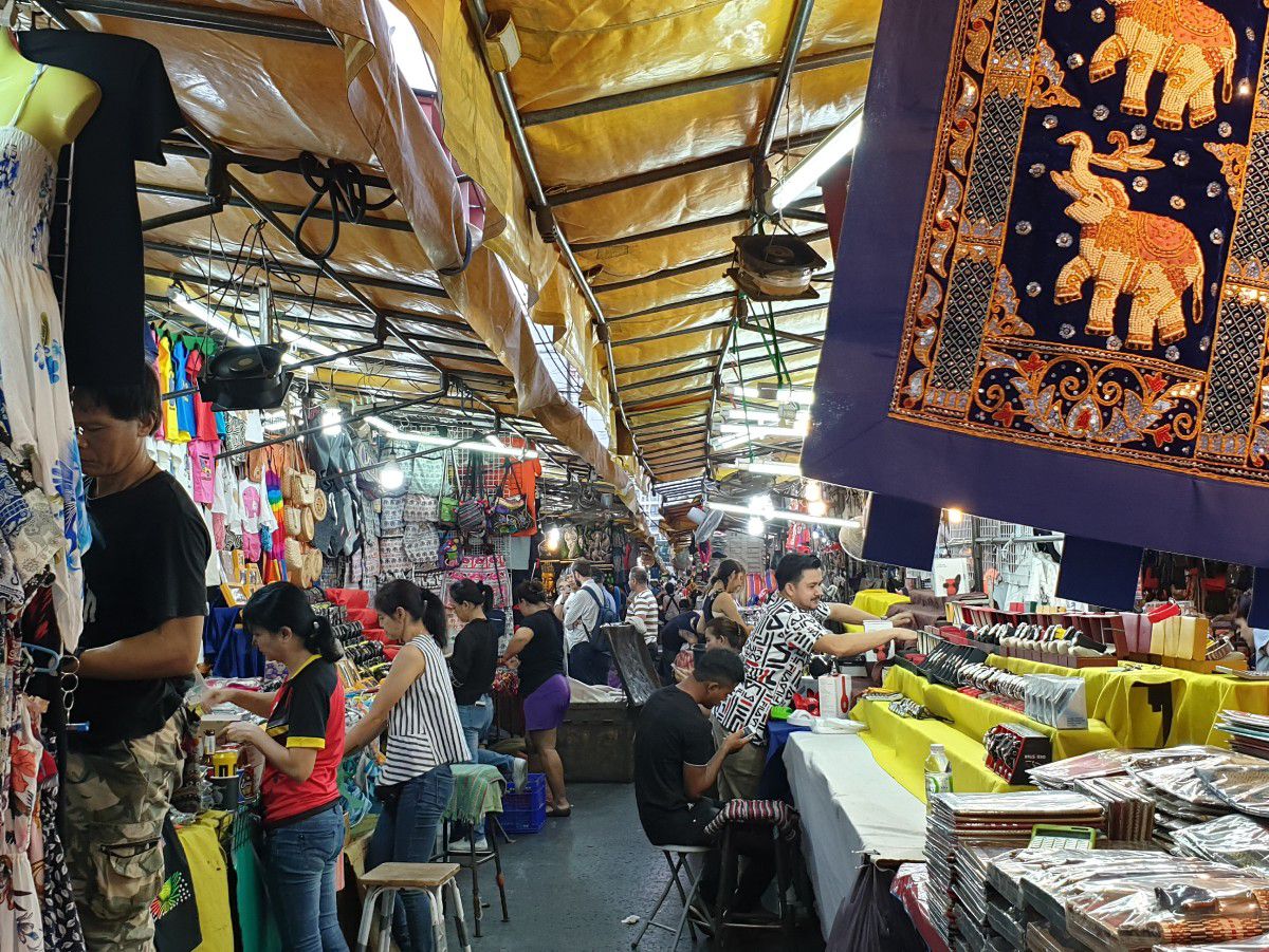 Busy indoor market with vendors, shoppers, and colorful handicrafts.