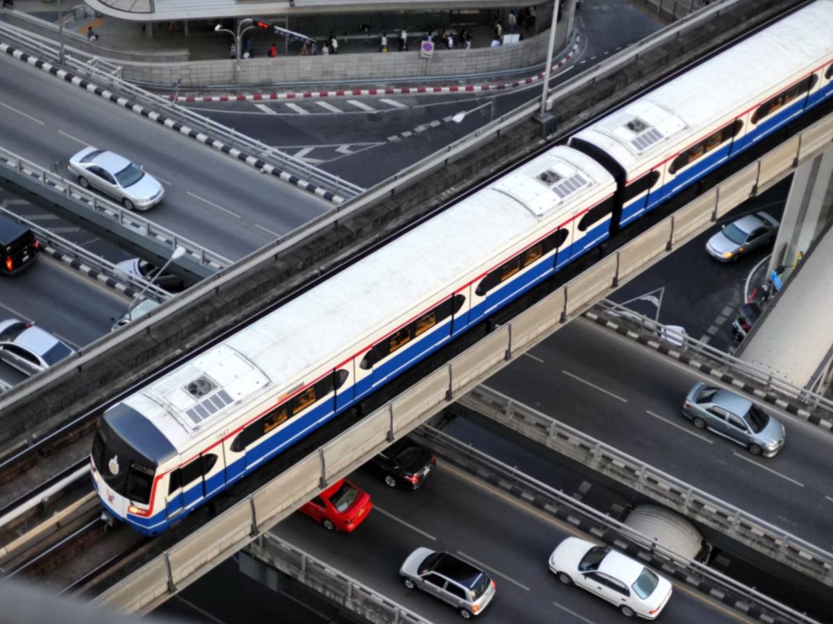 Elevated train passing above a busy city roadway.