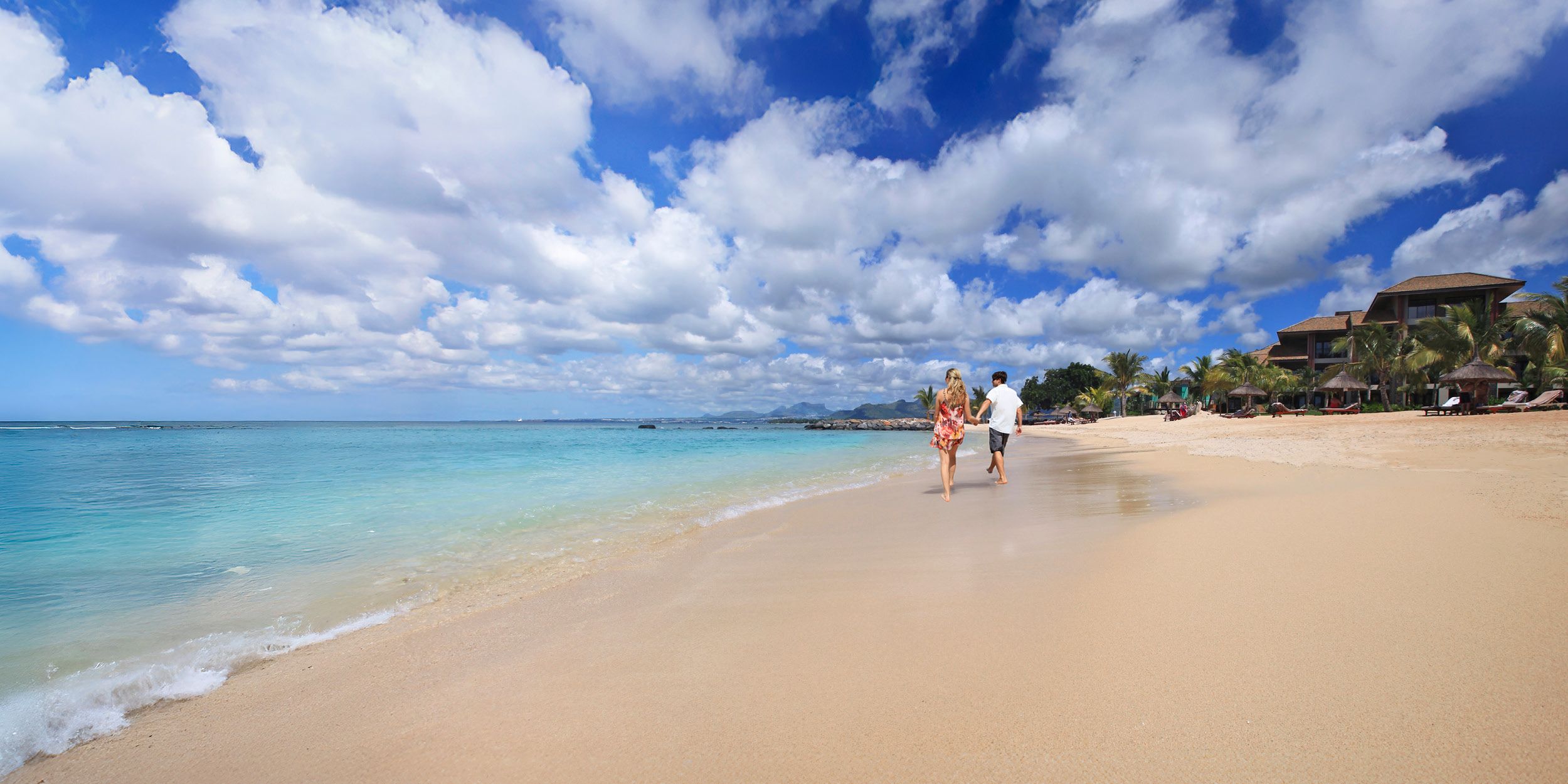 A couple walking on a beach on a  sunny day