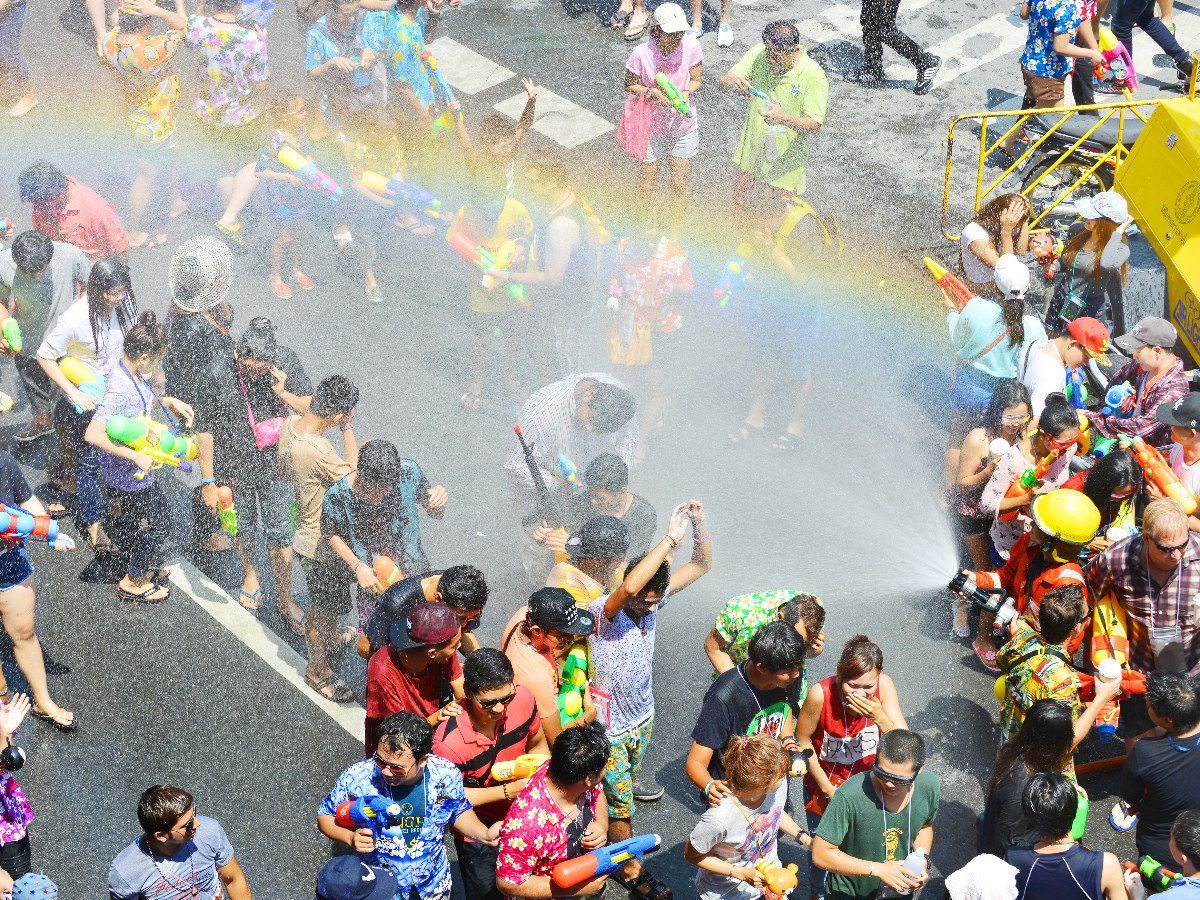 Crowds celebrating a lively water festival with colorful splashes and festive activities.