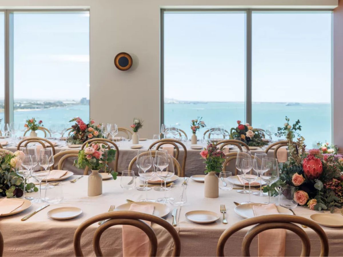 Beautiful special-occasion dining setup with ocean views and floral table arrangements.