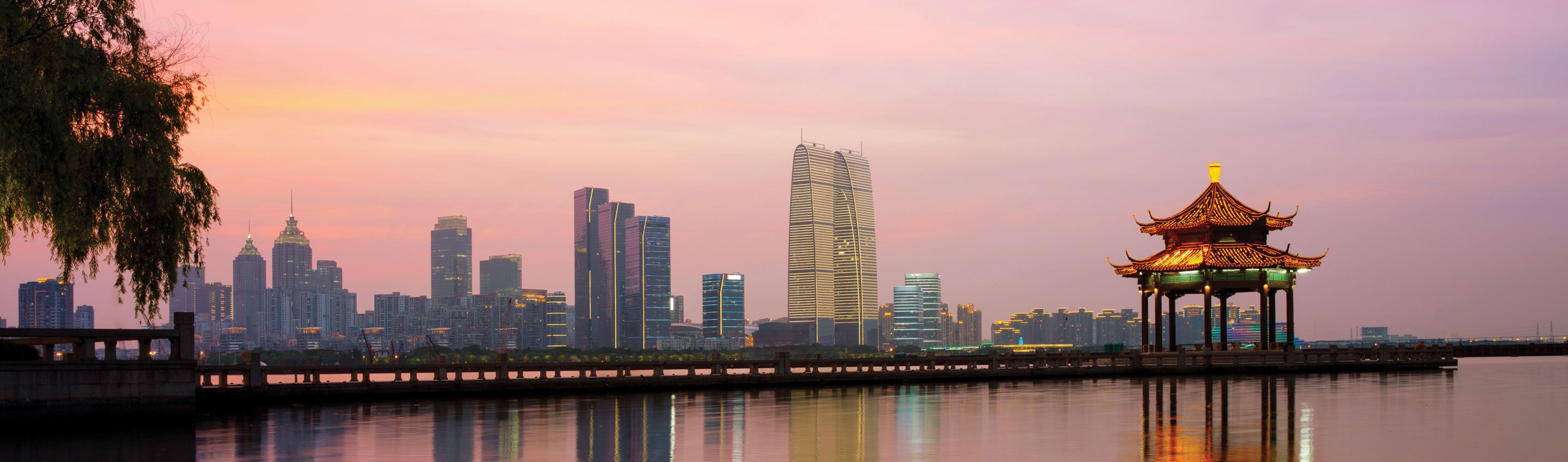 pink sunset skies reflect on the water and the suzhou skyline