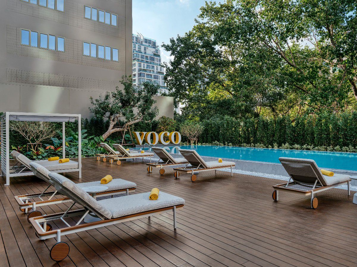 Outdoor swimming pool with lounge chairs surrounded by lush greenery.