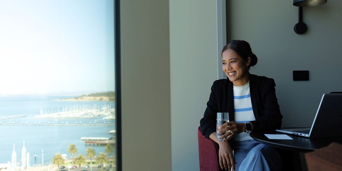 Woman sitting with laptop overlooking the ocean.