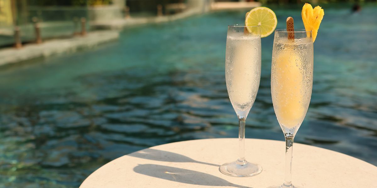 Two tropical drinks beside a poolside setting