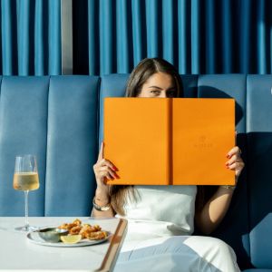 Woman dining while reading a restaurant menu with wine