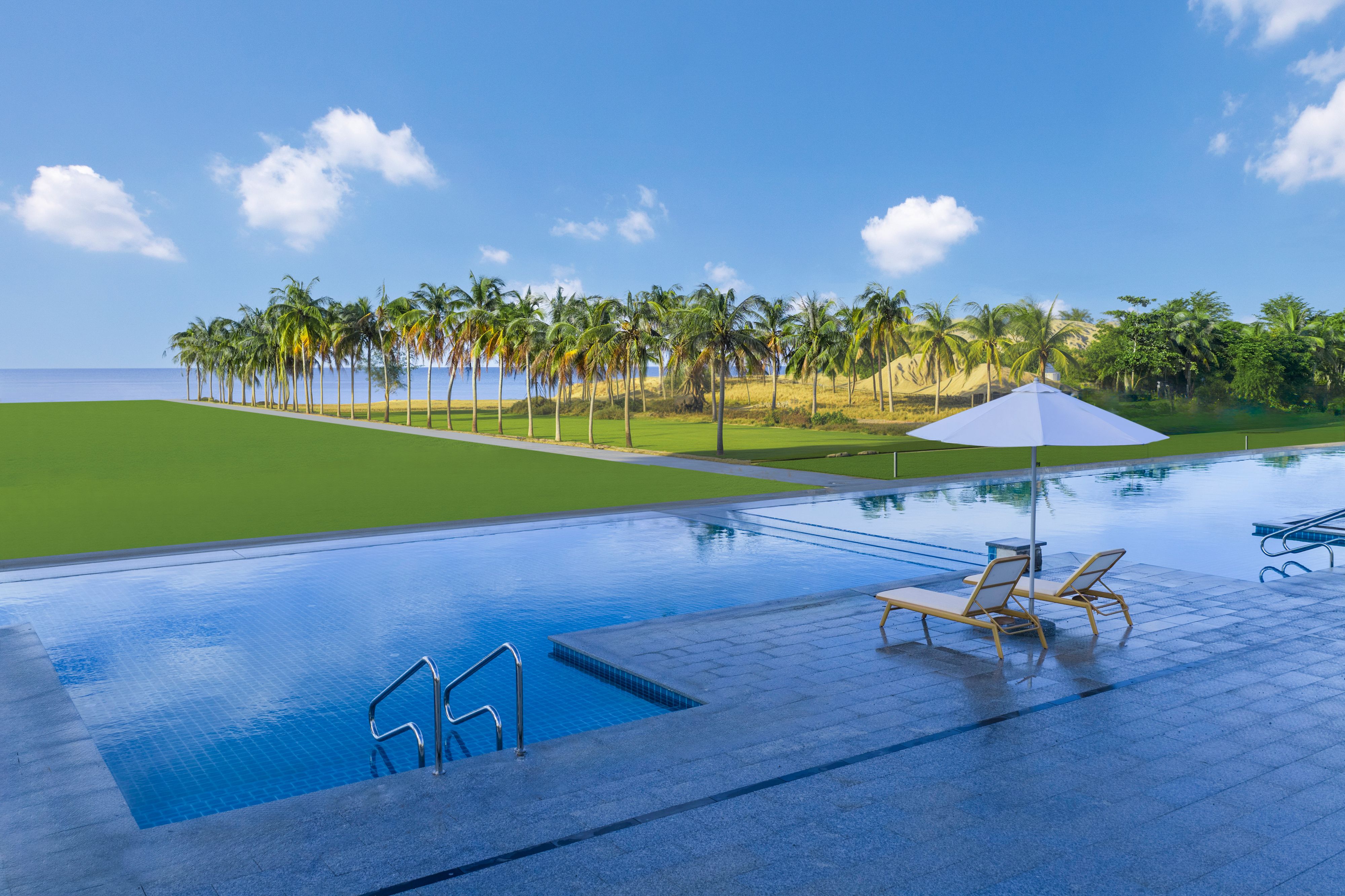 Outdoor pool with lounge chairs facing peninsula and palm trees.