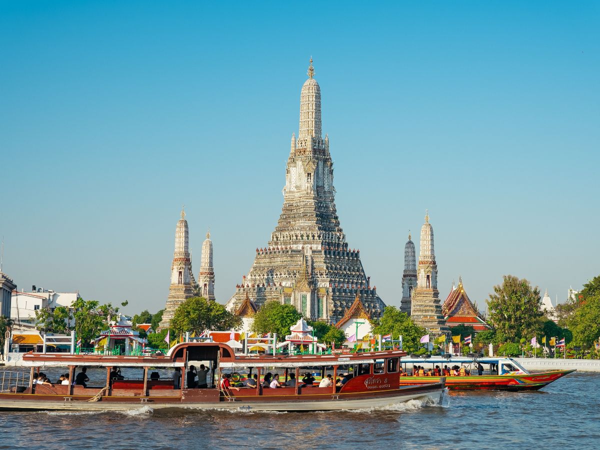 Riverside temple with boats cruising along the water.