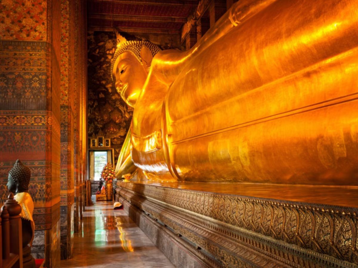 Reclining golden Buddha statue inside an ornate temple.