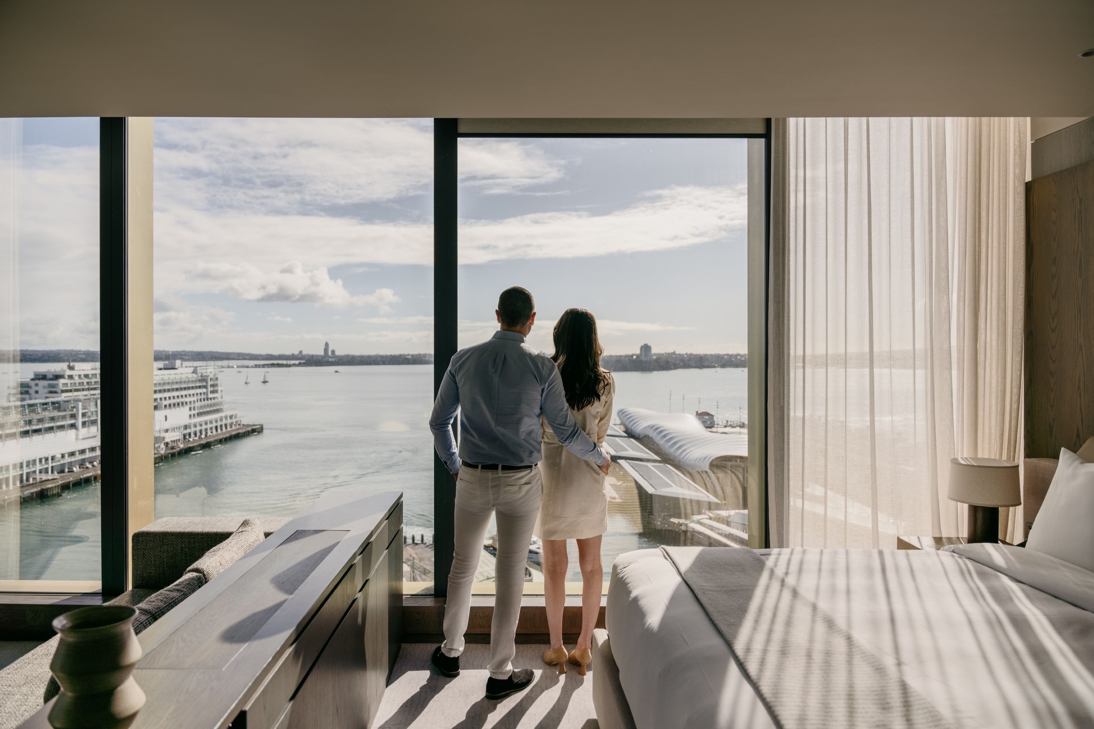 Couple looking out the window to water views in hotel room at InterContinental Auckland.