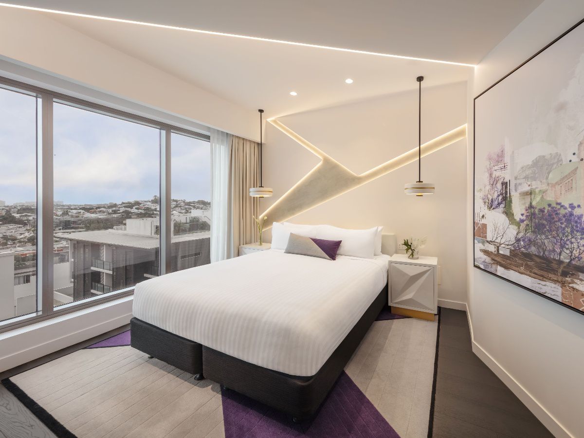 Modern hotel bedroom with city view through windows