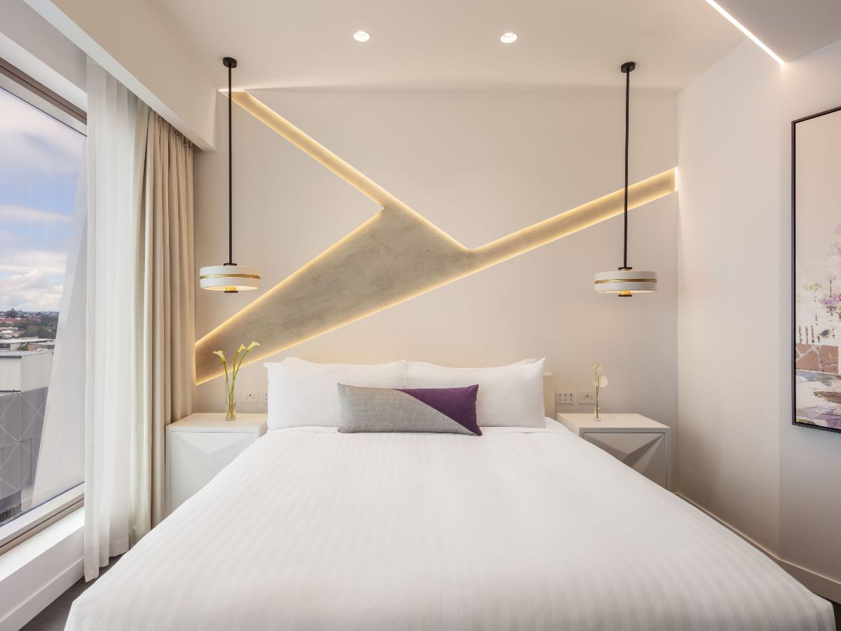 Modern hotel bedroom with city view through windows