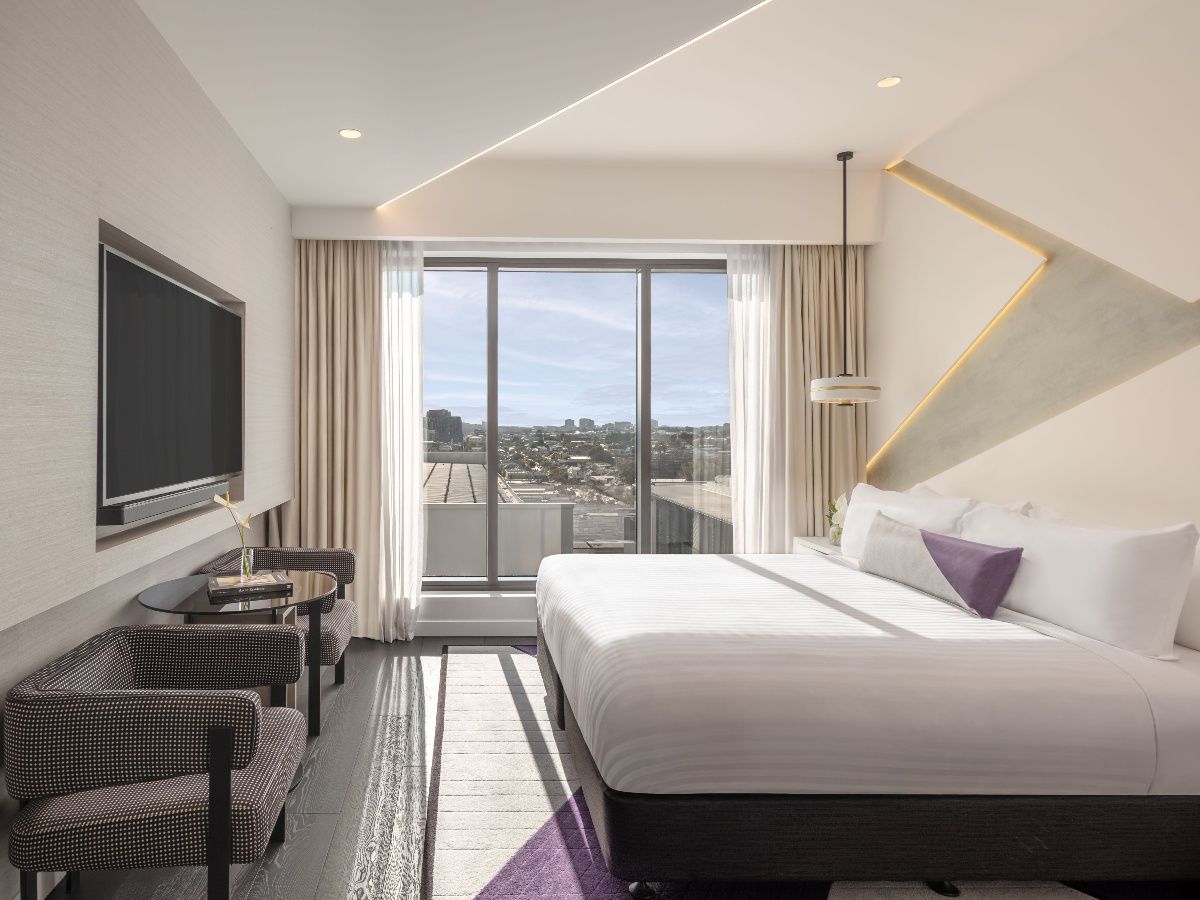 Modern hotel bedroom with city view through windows