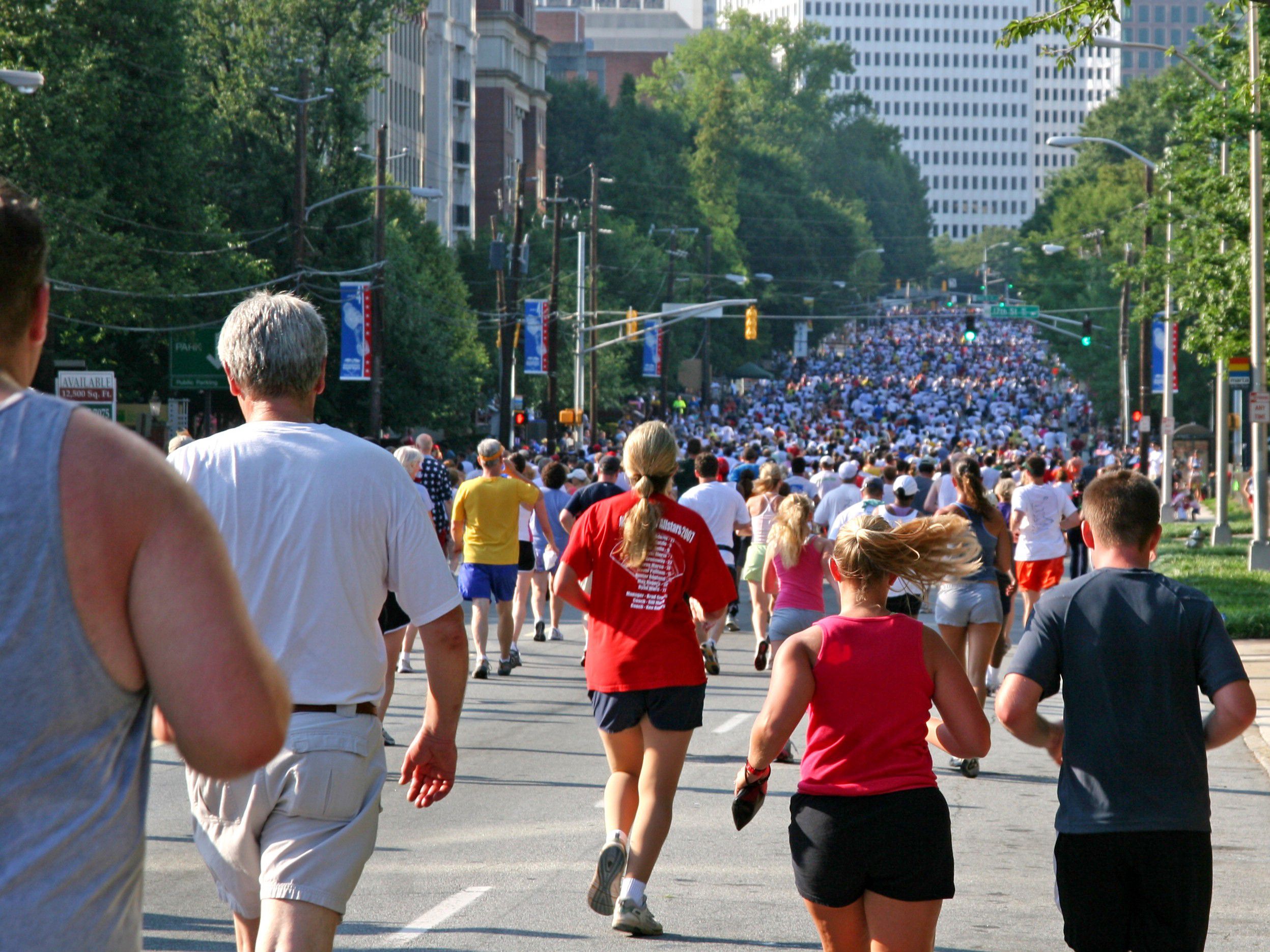 Large crowd running down a city street during a road race.