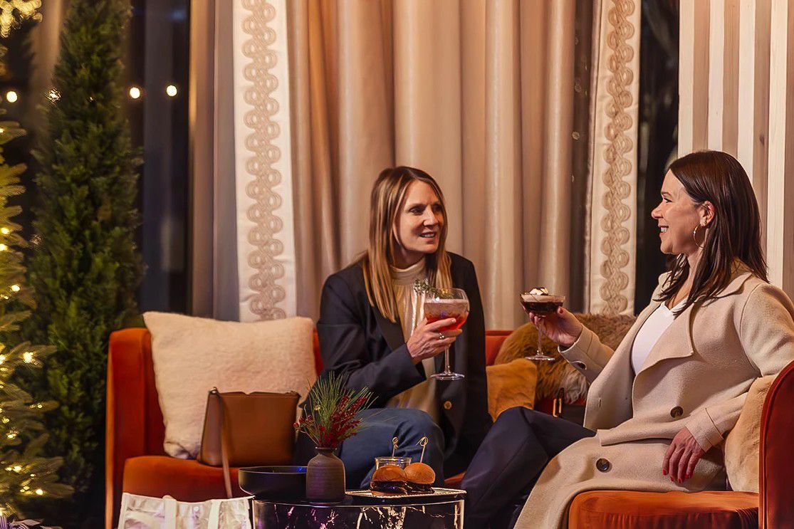 Two guests enjoying cocktails in a festive holiday lounge.