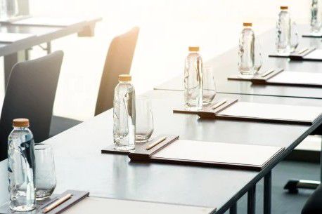 Conference room table setup with notepads, glassware, and bottled water