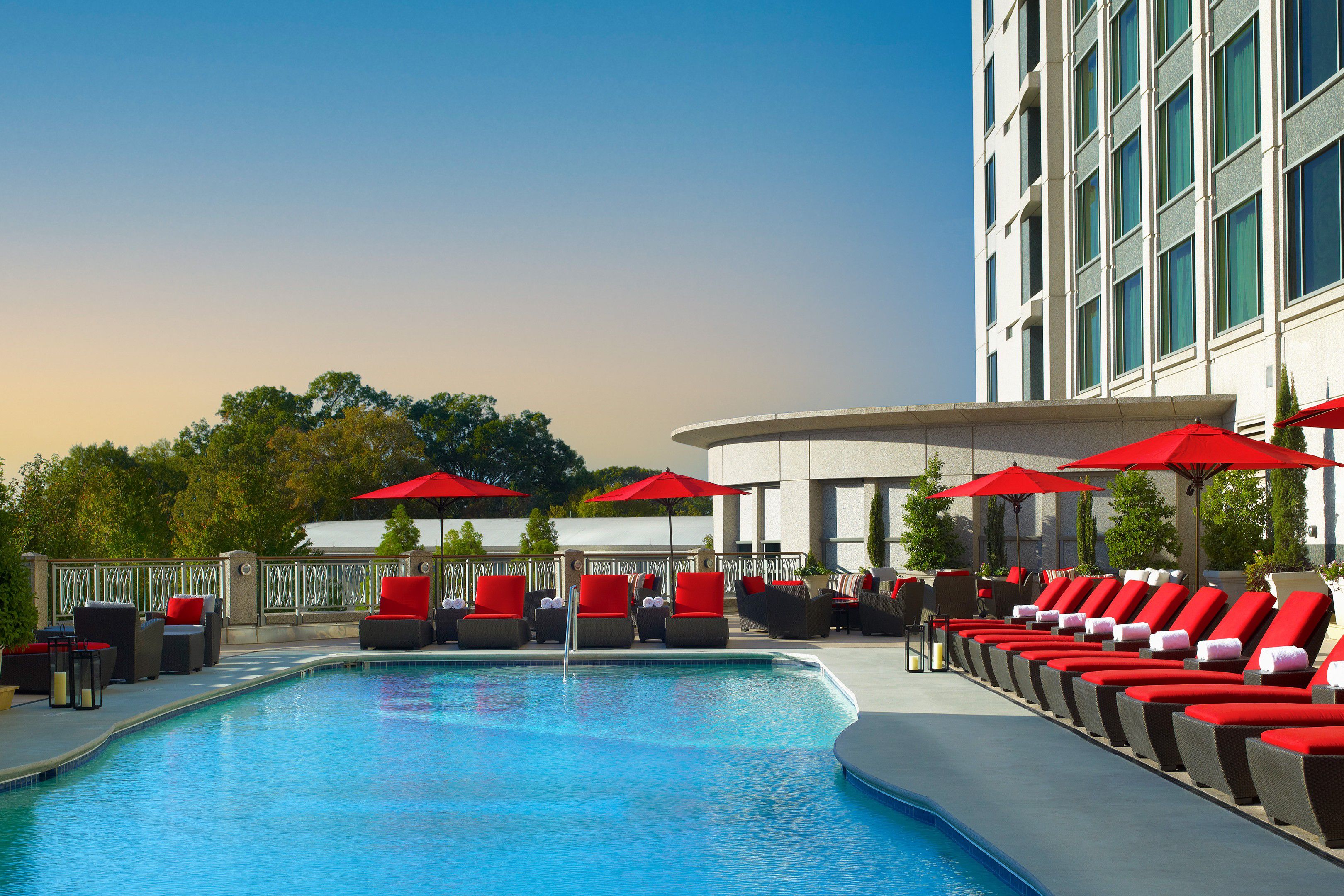 Outdoor hotel pool with red lounge chairs and umbrellas beside the InterContinental Buckhead Atlanta