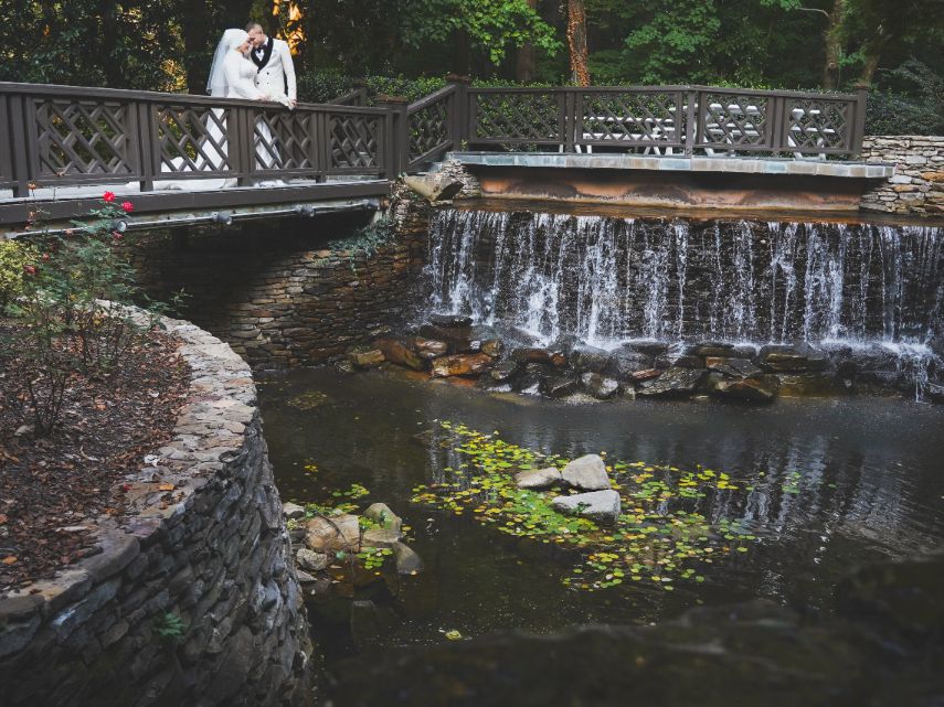 Bride and groom on bridge over creek