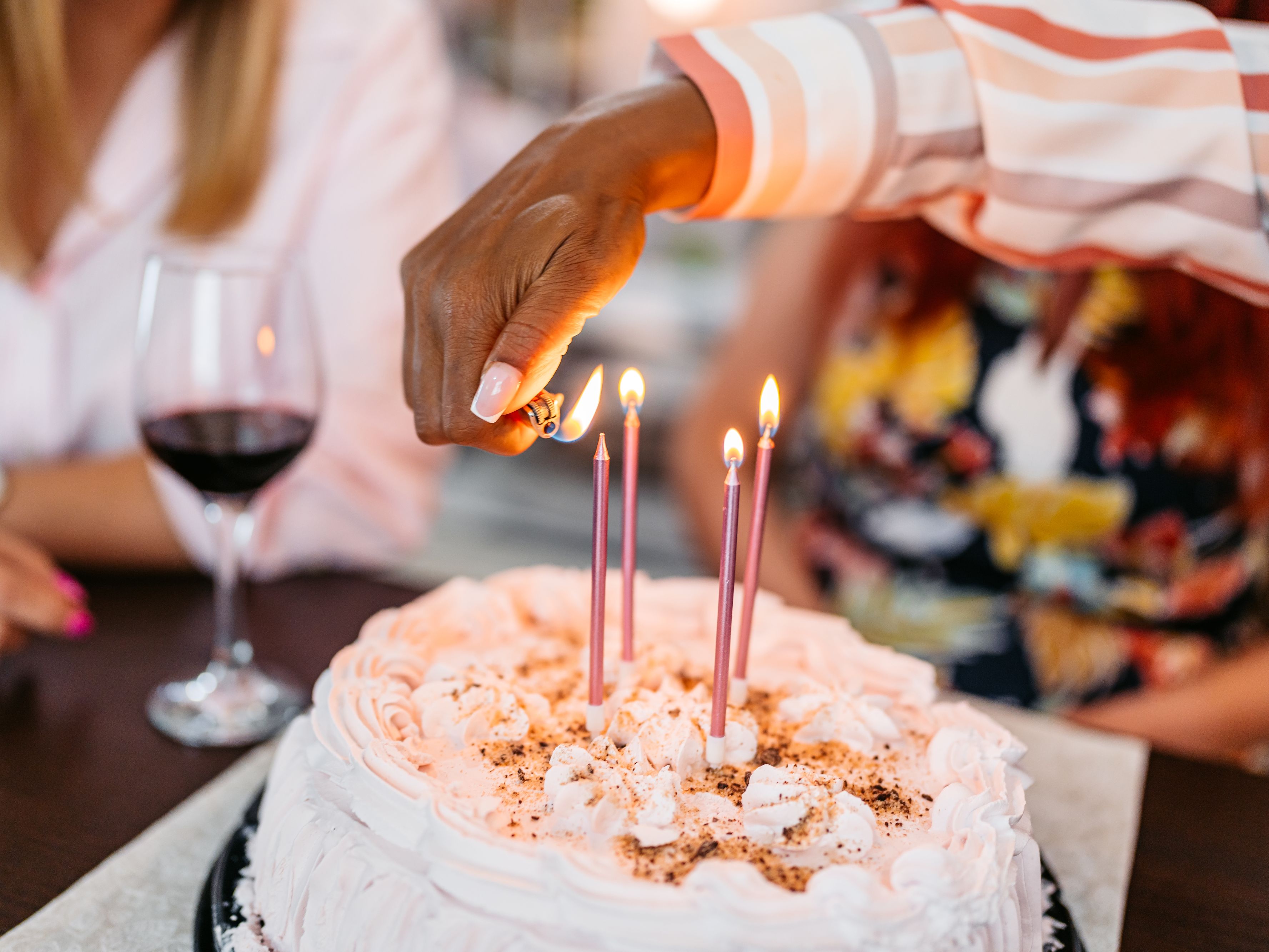 person lighting a birthday cake