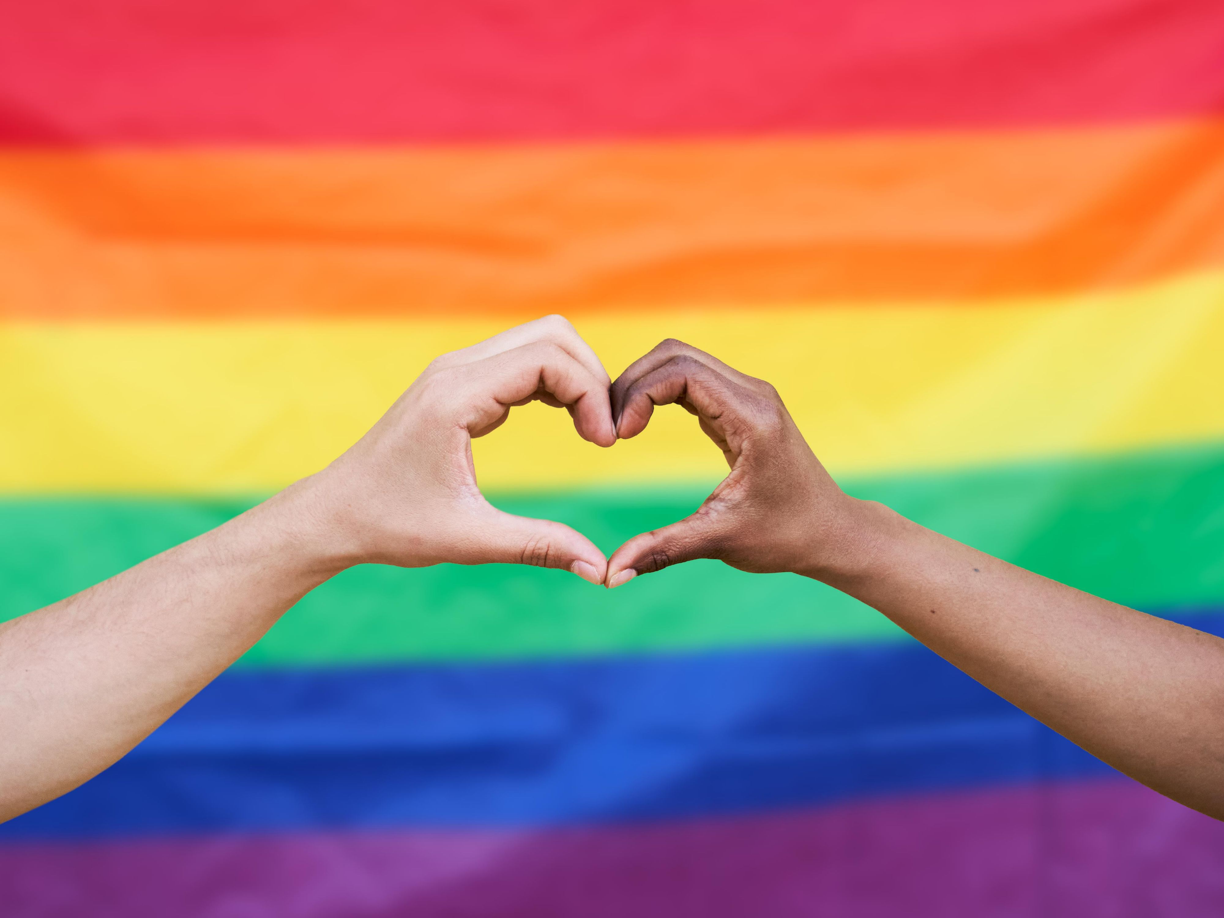 Heart hands in front of a pride flag