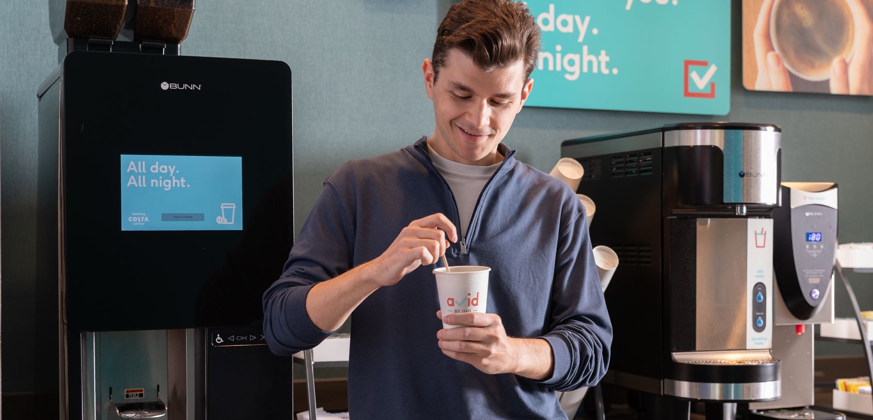 Man stirring his coffee and smiling next to the bean-to-cup coffee machine