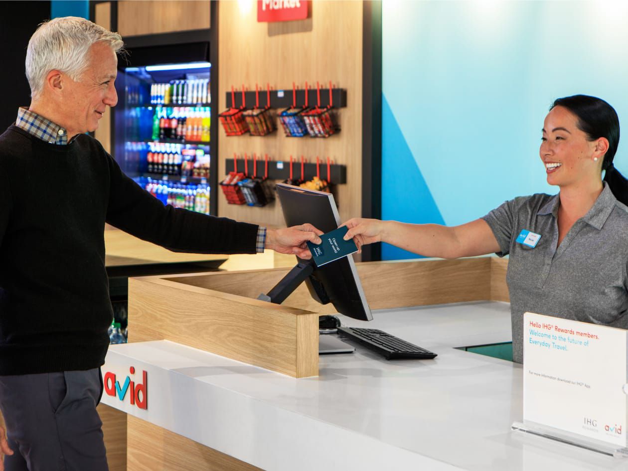Man receiving his hotel key from woman working the check-in desk