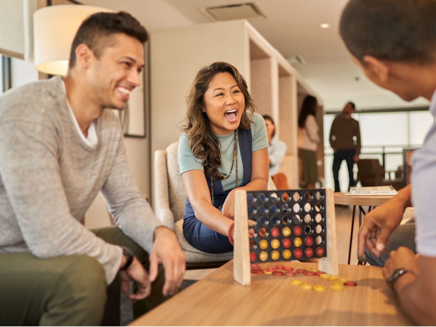 Friends playing a board game and laughing in a lounge