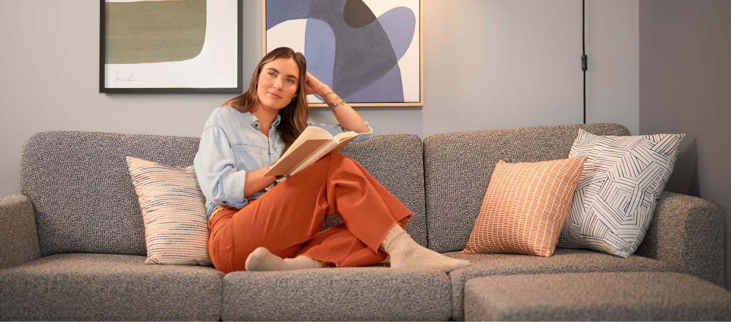 Kitap okurken kanepede dinlenen bir kadın.