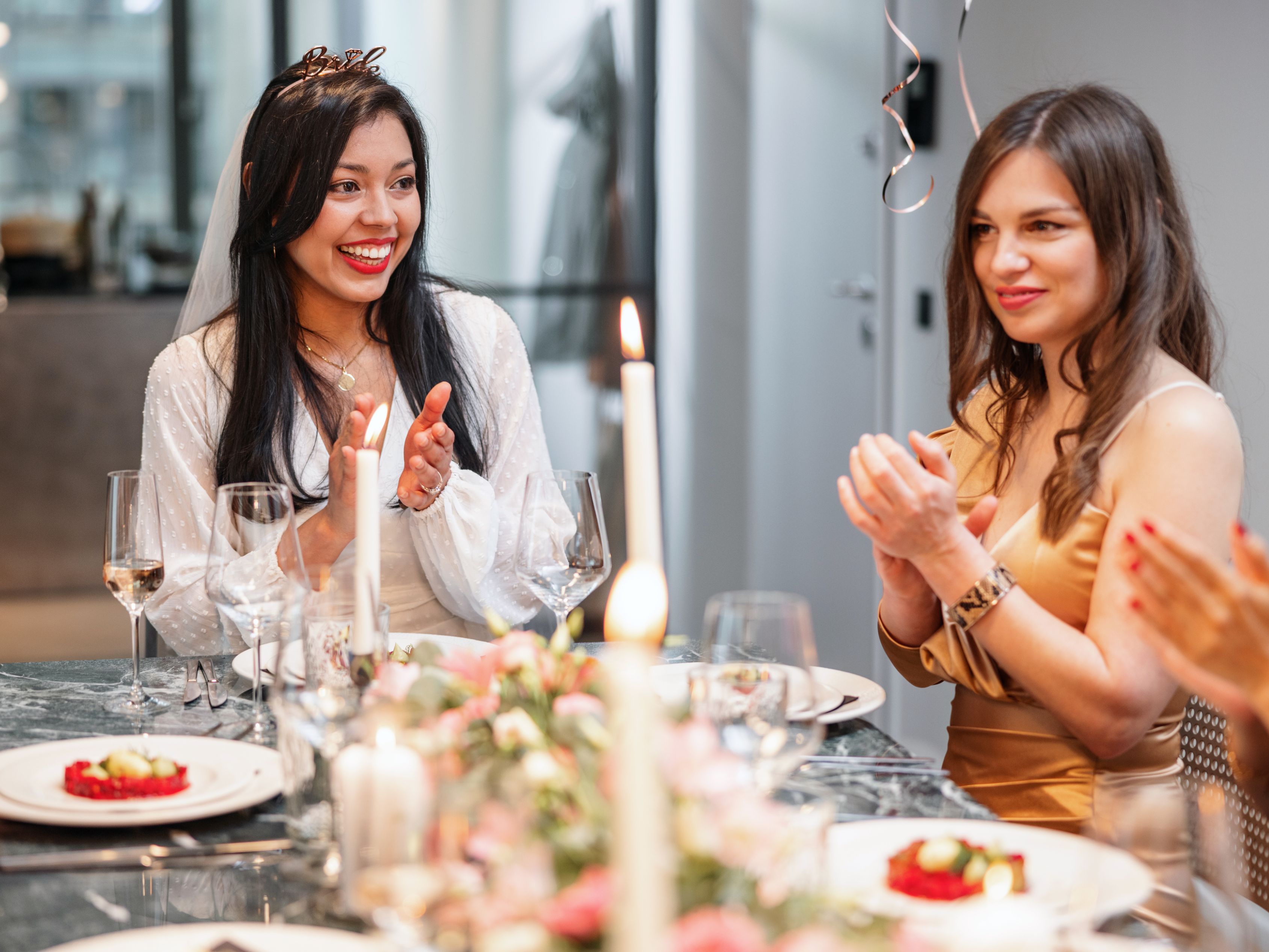 Bride and bridesmaid celebrating at a table set up for a wedding celebration.