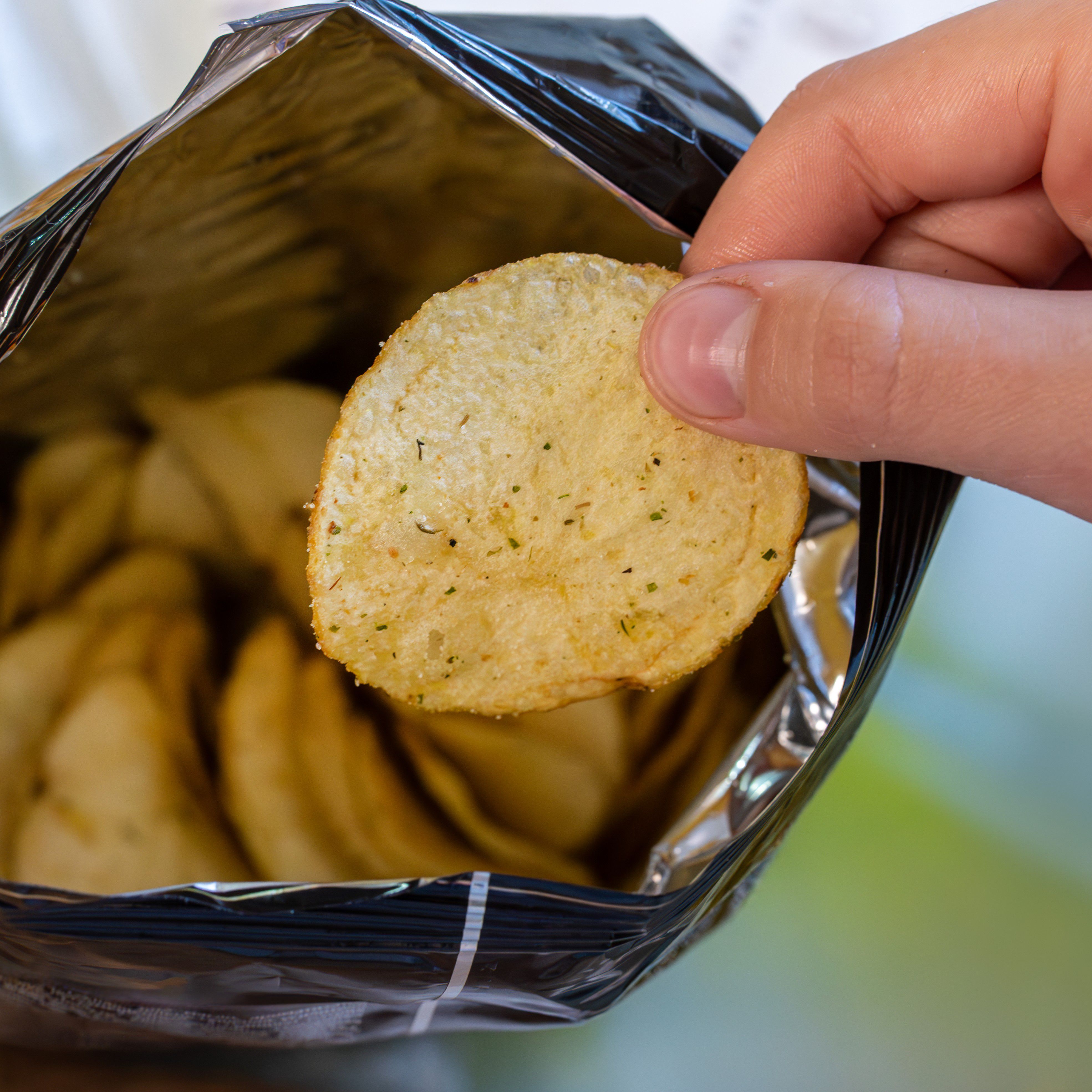 Hand picking a potato chip out of a bag