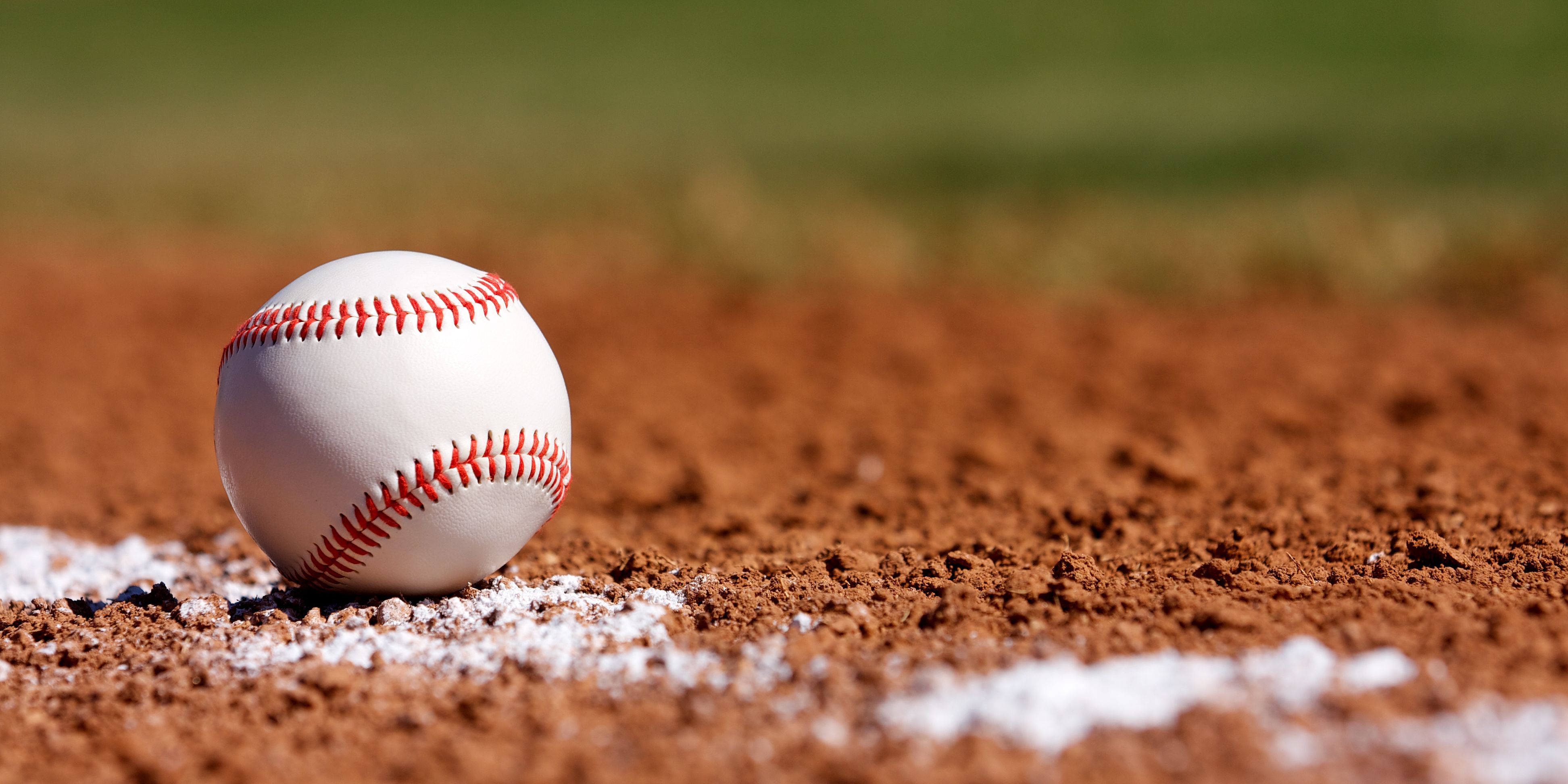 Baseball sitting in dirt on the baseball field.