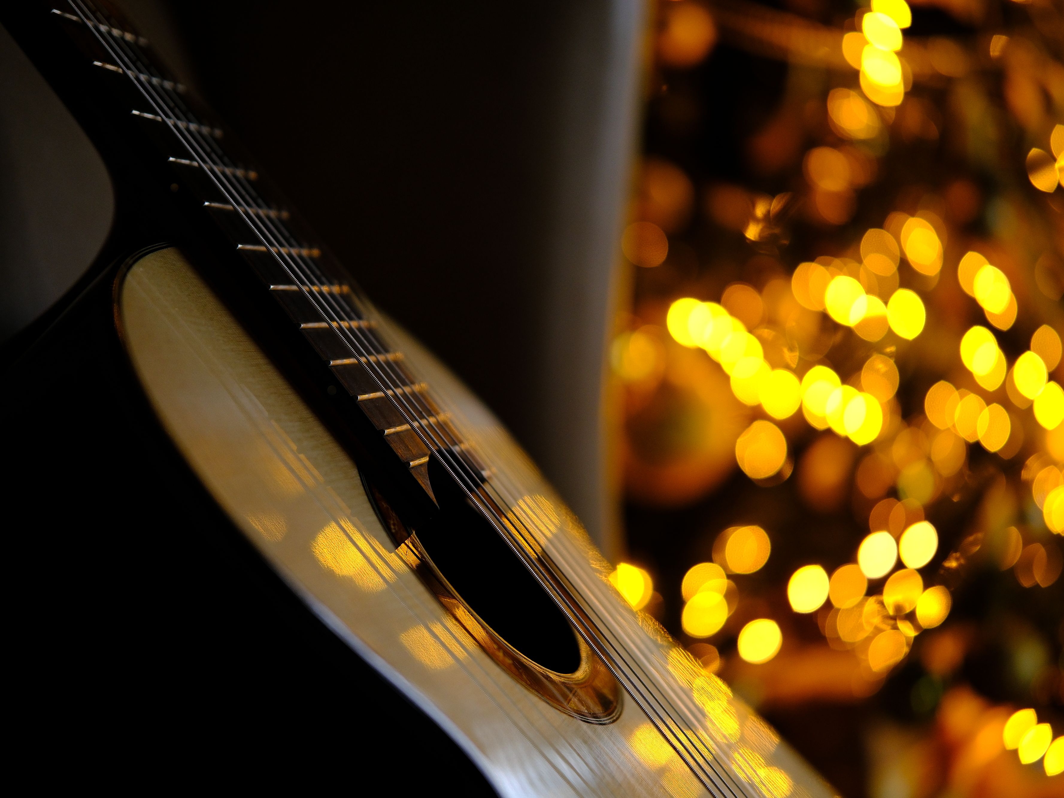 Acoustic guitar with christmas lights in background