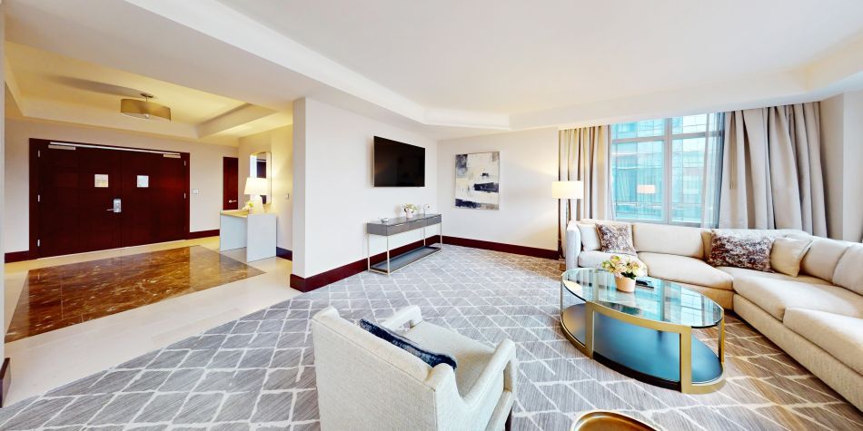 Ambassador Suite living room area featuring a couch, tv, and view of entry way.