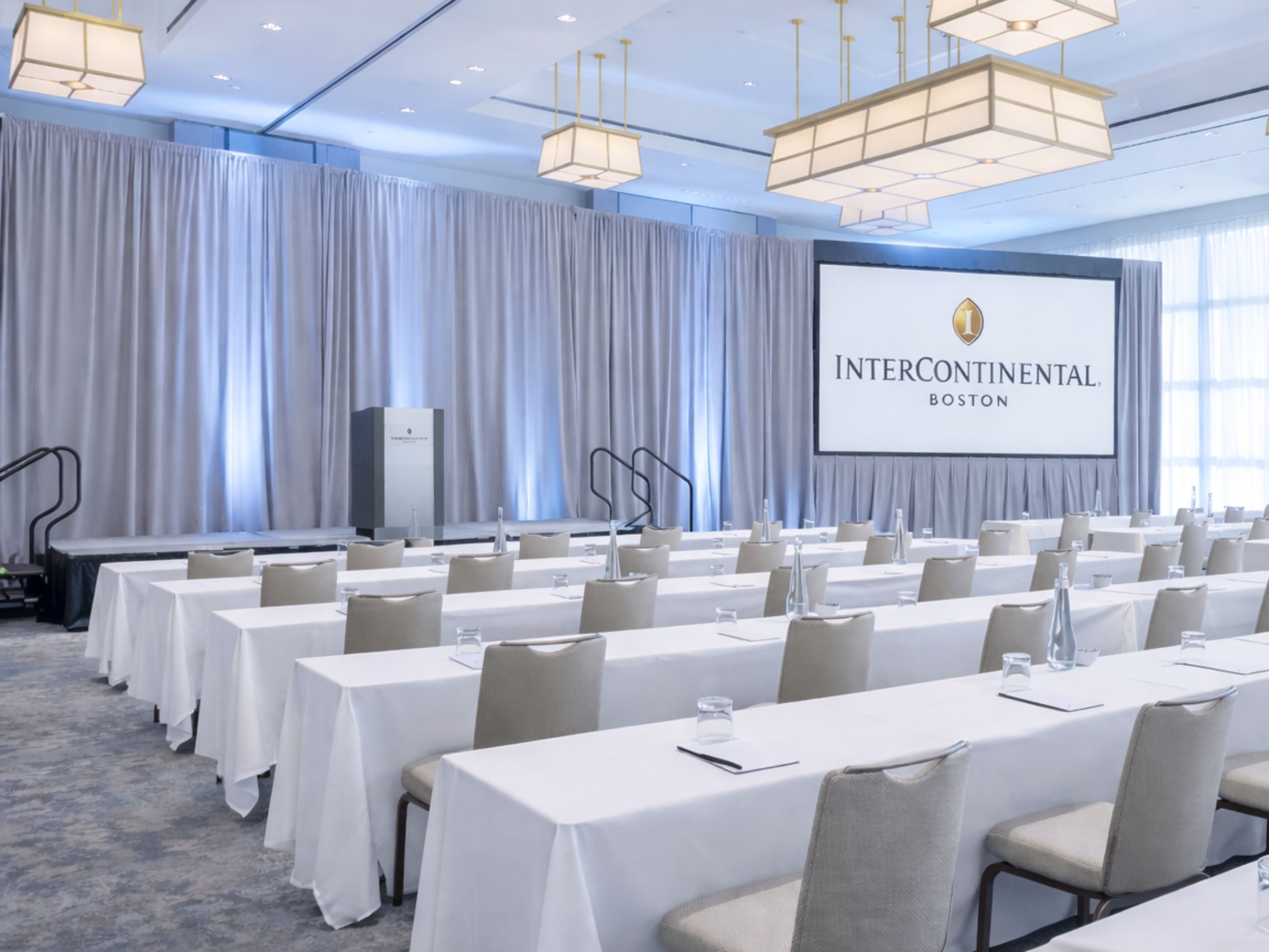 Ballroom set up for a conference with rows of tables and seating.