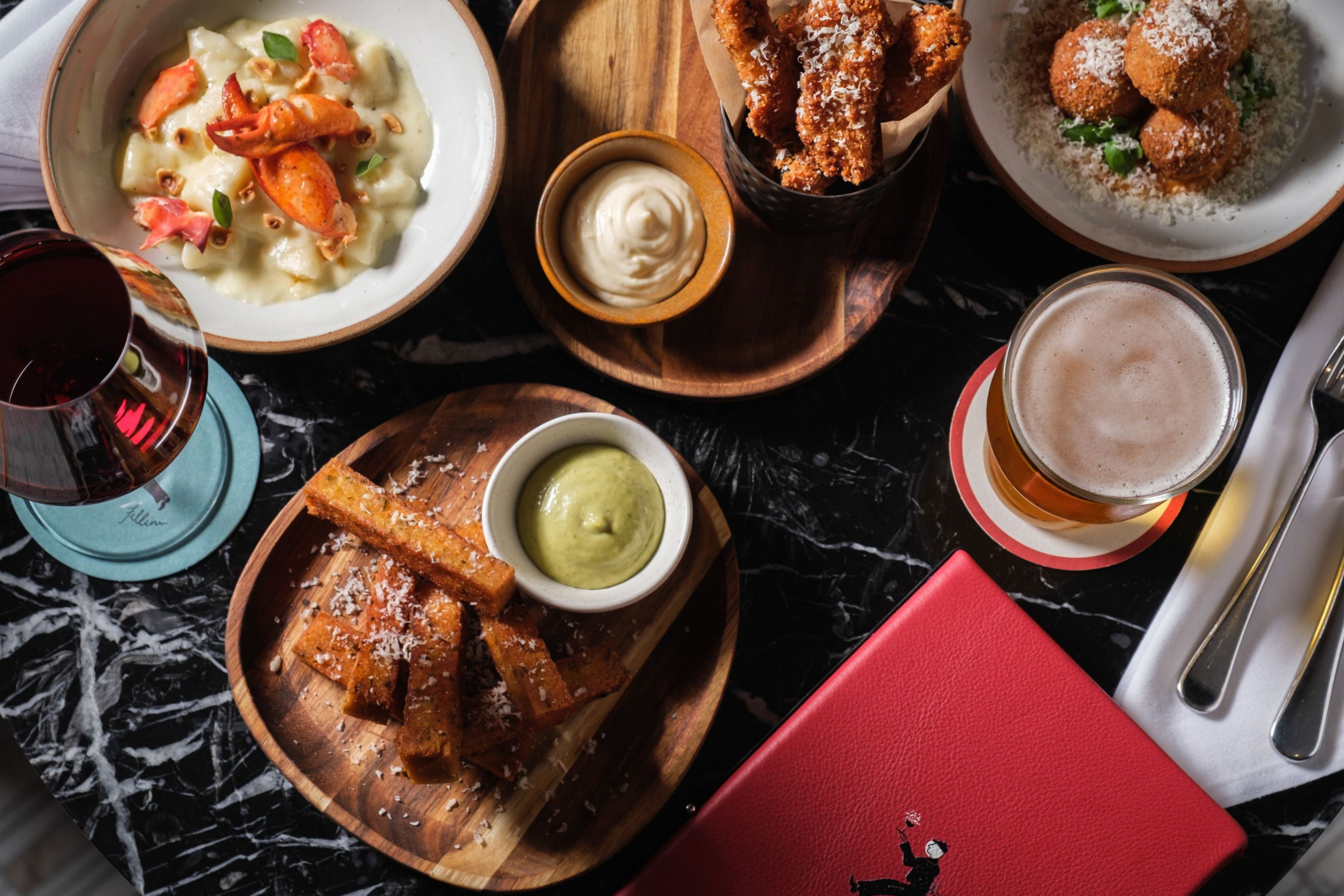 Top-down spread of small plates, wine and beer.