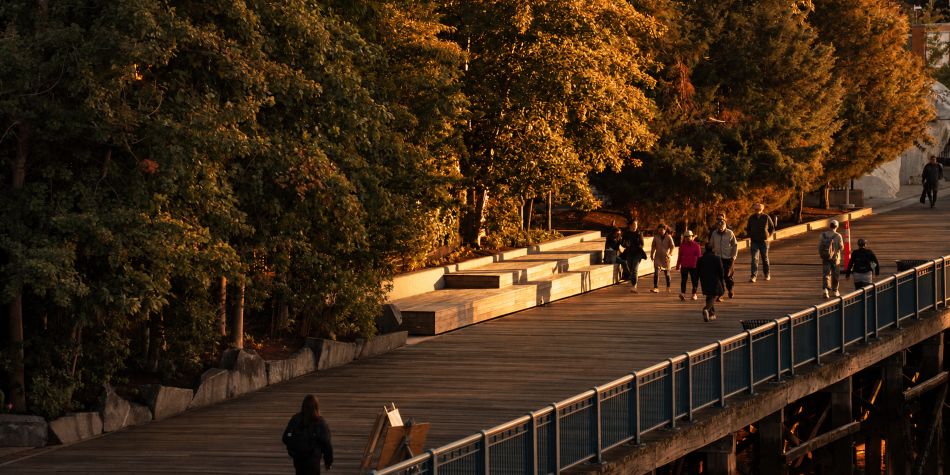 People walking along Boston Harborwalk  at sunset.