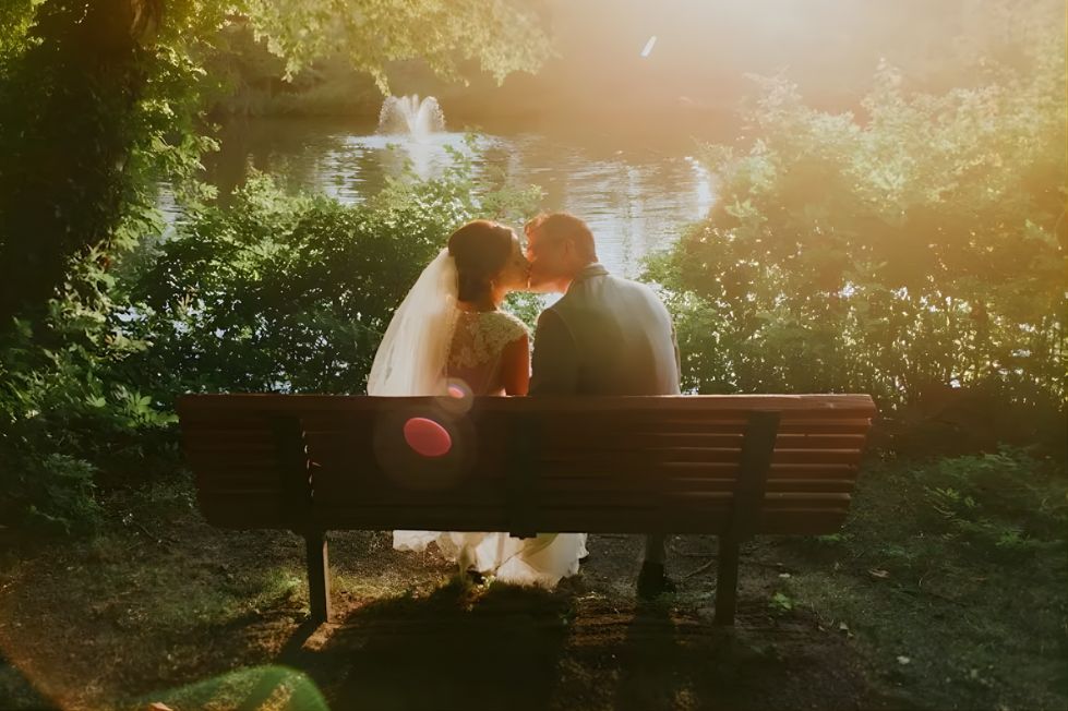 Bride and groom kissing on a bench.
