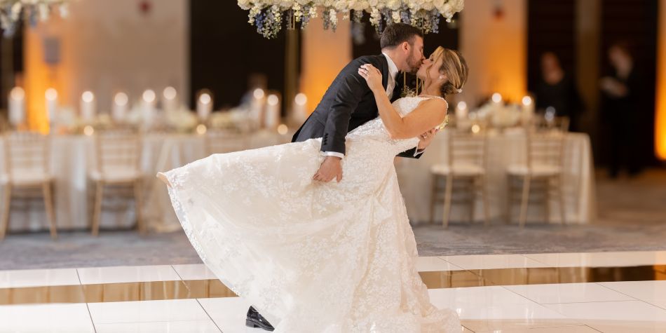 Groom dipping and kissing his bride on the dance floor.
