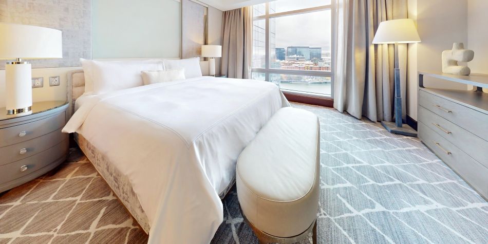 Club InterContinental suite bedroom featuring a king bed and views of Boston Harbor through floor-to-ceiling windows.