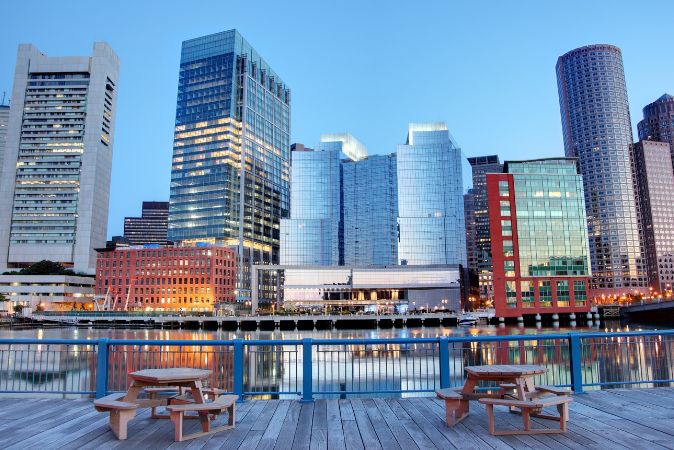 Picnic tables on dock overlooking Boston Harbor with view of IC Boston.