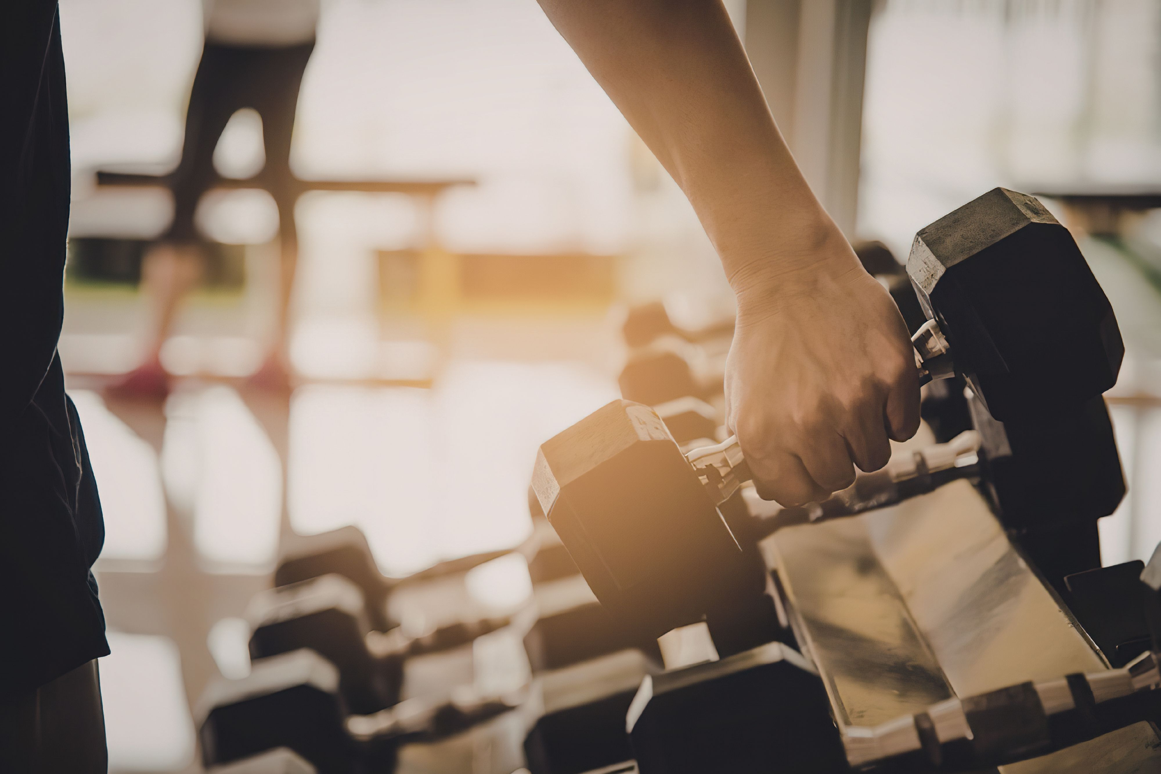 Close up of guest's hands picking up a dumbell.