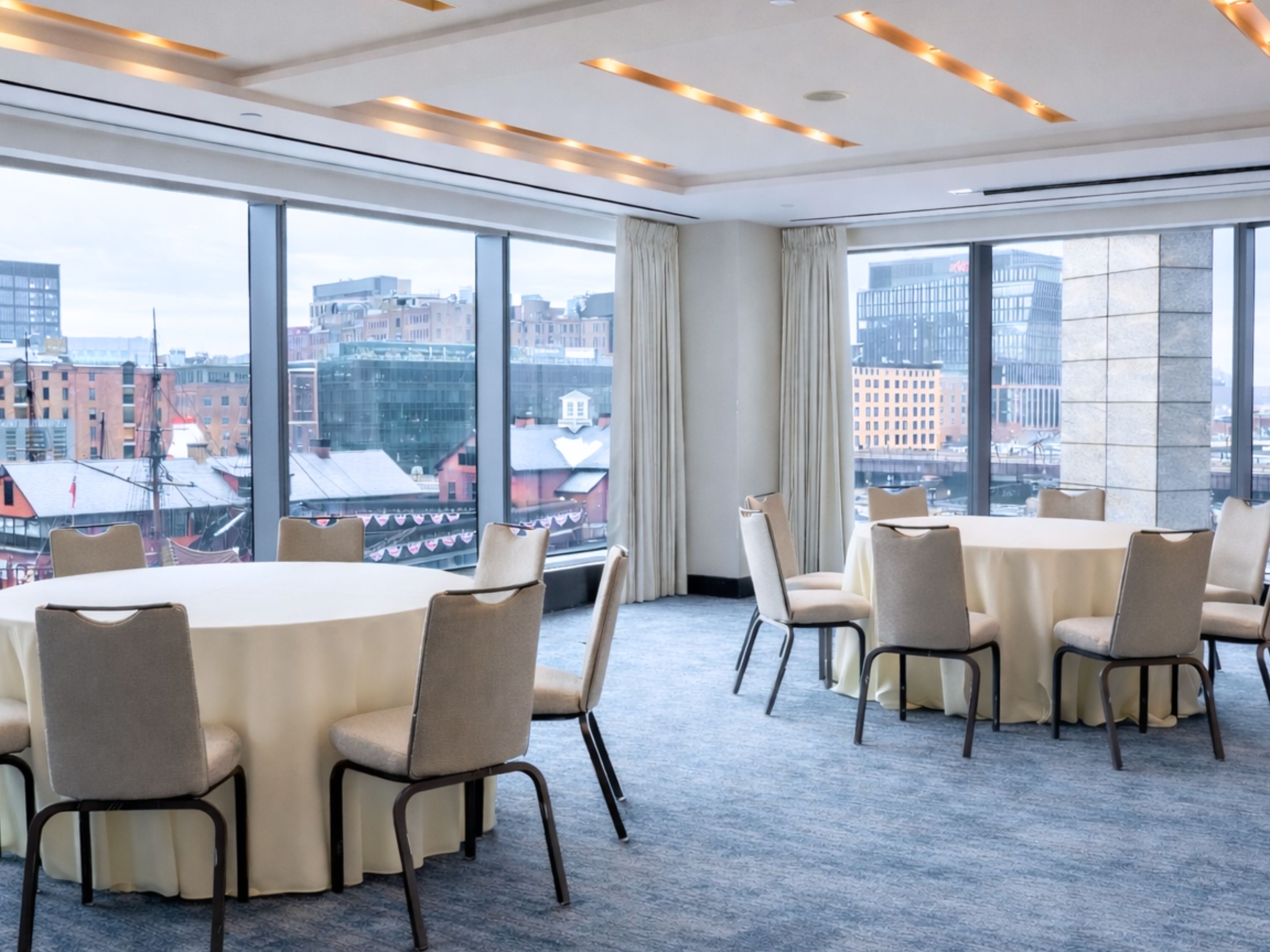 Event room set up with round tables, with floor to ceilings windows showing a view of the city.