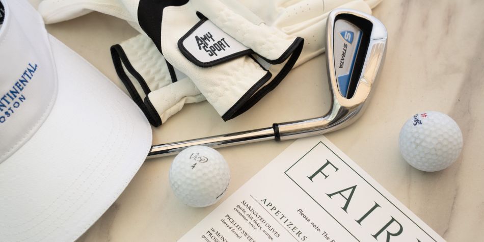Fairway menu on display next to a golf club, golf balls, golf gloves, and an IC Boston logo hat.