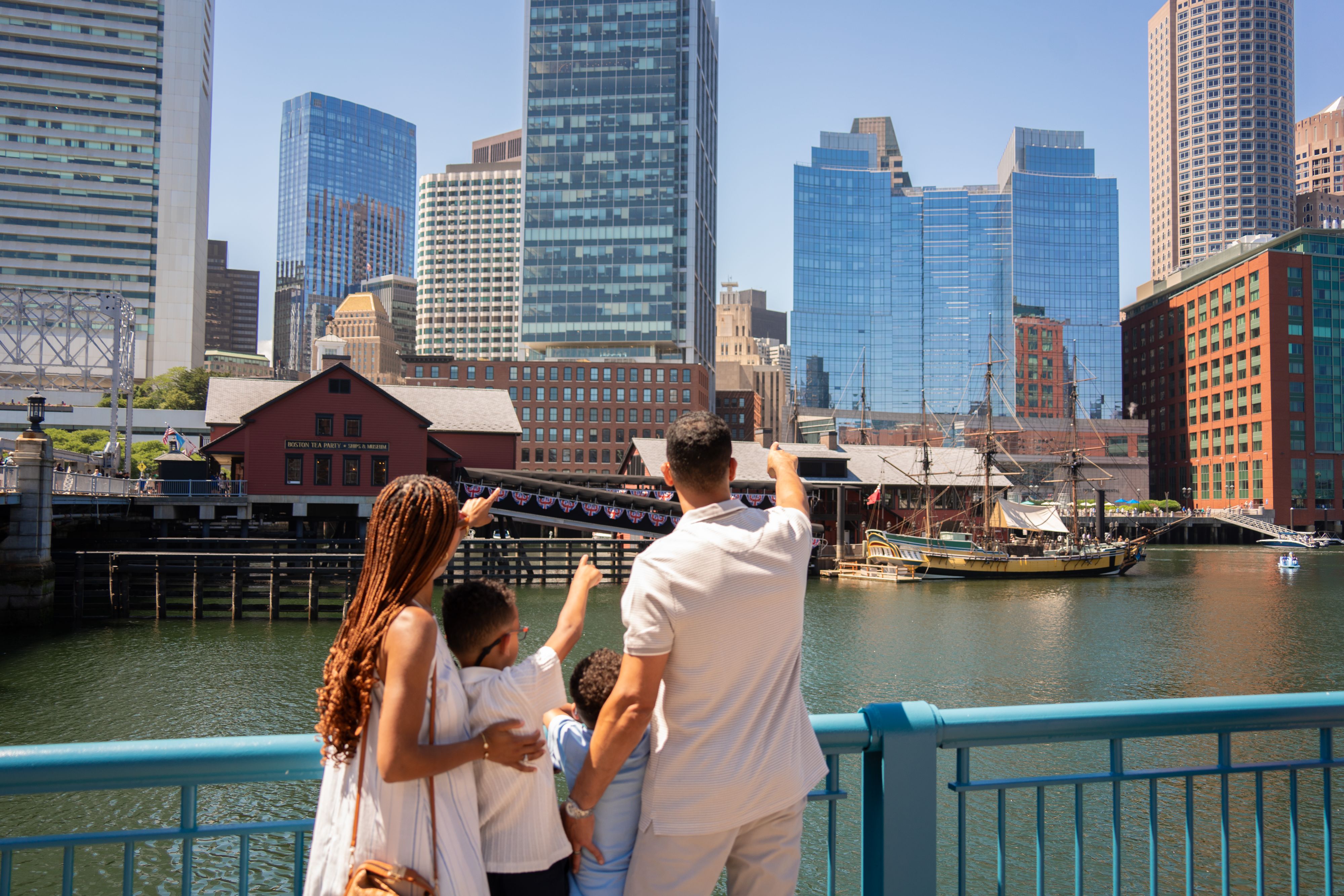 Family at Boston Harbor pointing at the Tea Party Ships & Museum.